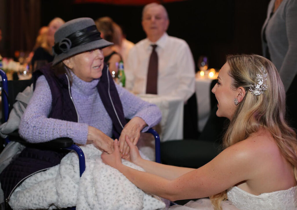 A photo of a woman holding her grandmas hands.